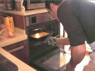 Joven metiendo bandeja con bizcocho en horno