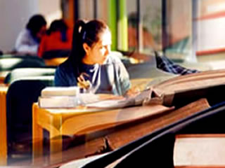 Chica en biblioteca estudiando junto a libros